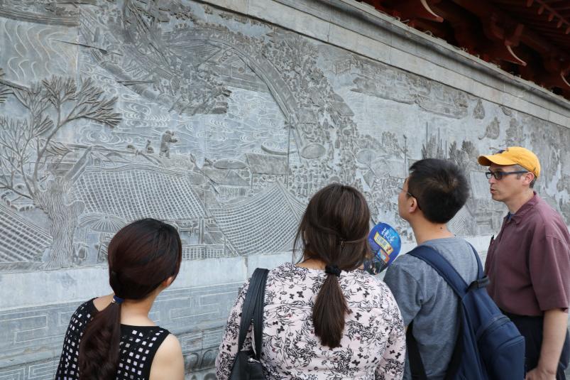 在景观期间，教授和学生研究中国黄河地区的一个浮雕板...